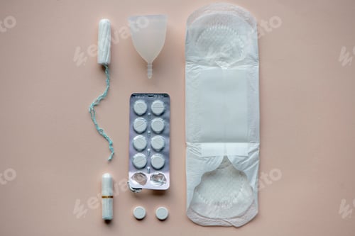 Preview: Female hygiene products lay out on a bed. Paracetamol, Sanitary pad, tampon, Chocolate,