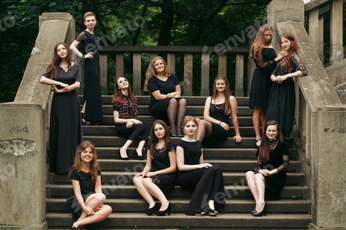 Preview: gorgeous women group in black dresses posing on stairs in the city