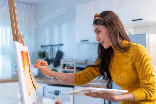 Preview: Asian young talented woman artist coloring on painting board in house.