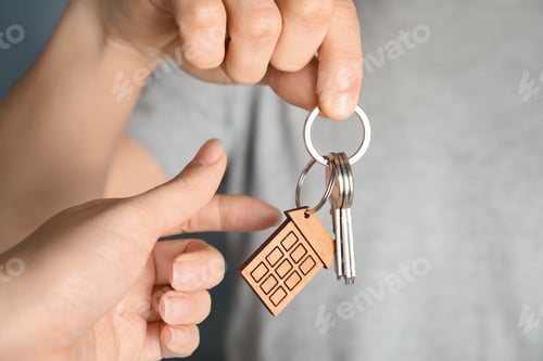 Preview: Man giving house key with trinket to woman, closeup