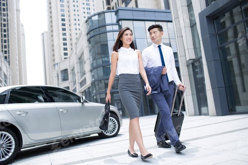 Preview: Confident business people walking with wheeled luggage