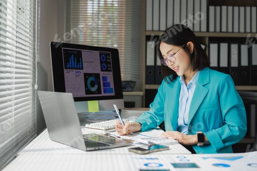 Preview: Businesswoman analyzing data graphs working on documents in office