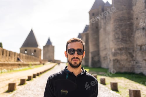 Preview: Caucasian man standing in a path next to the wall of a medieval castle