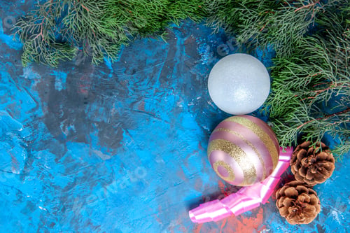 Preview: top view pine tree branches pinecones xmas tree balls ribbon on blue-red background with copy space