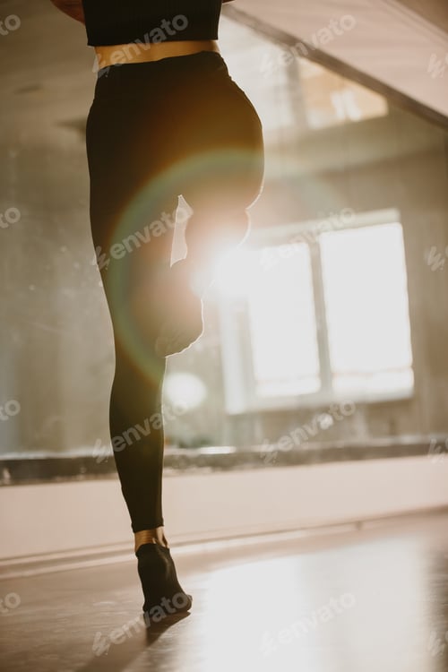 Preview: A young woman is engaged in modern dance choreography in a ballet studio. Legs close-up.