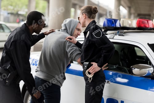 Preview: policeman and policewoman arresting young man in hoodie
