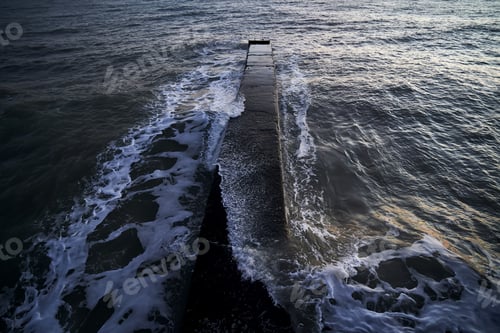 Preview: Landscape with a stone pier and raging waves in the sea.