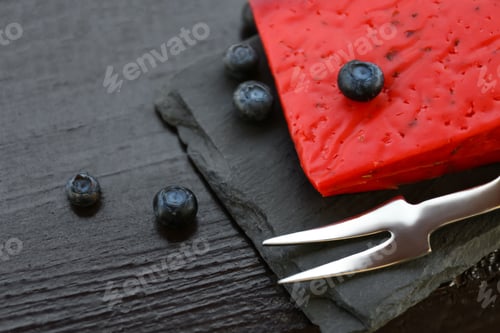 Preview: Delicious red cheese, blueberries and fork on black wooden table, closeup