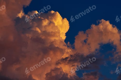 Preview: Fluffy clouds tinted orange by the sunset
