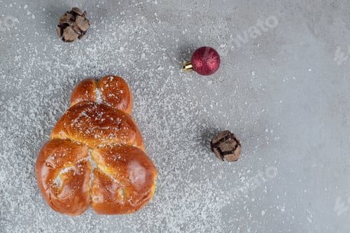 Preview: Christmas and pine balls surrounding a sweet bun on marble background