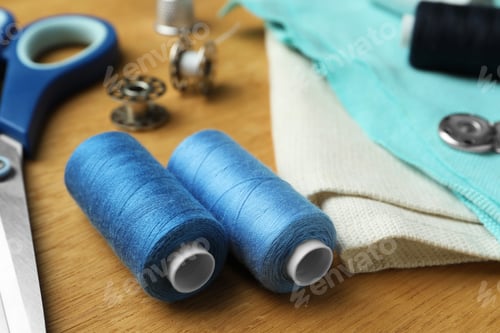 Preview: Spools of threads and sewing tools on wooden table, closeup