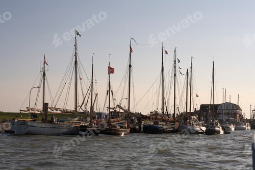 Preview: Boats and sailboats docked at a waterfront harbor under a clear sky. North Sea, Germany