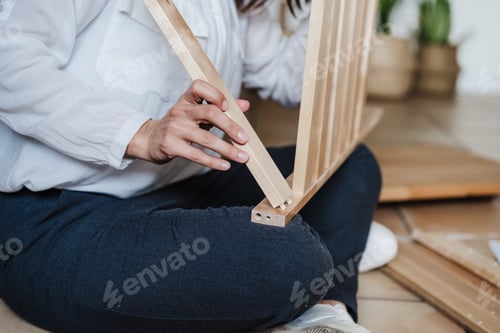 Preview: close up of young woman assembling furnitures. DIY concept