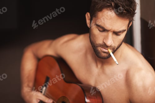 Preview: Working on his latest song. Cropped shot of a shirtless young man playing guitar at home.