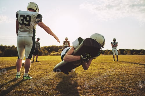Preview: American football players practicing tackles on a football field