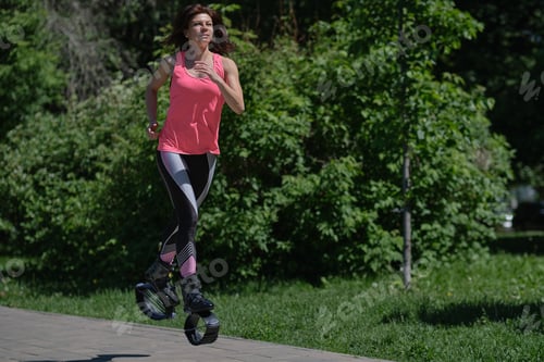 Preview: beautiful woman runs along the path in the park, legs in kangoo jumping shoes
