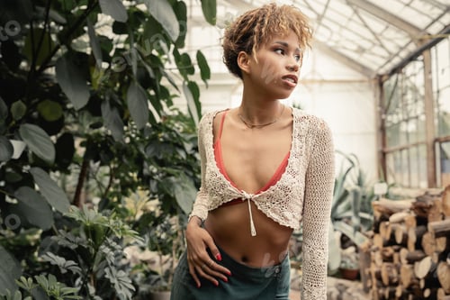 Preview: Portrait of modern young african american woman in summer knitted top and skirt touching hip while