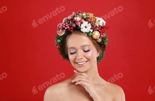 Preview: Beautiful young woman wearing Christmas wreath on red background