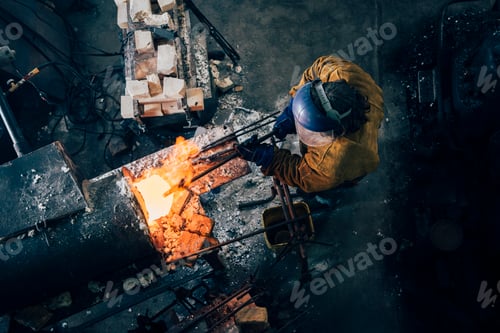 Preview: Overhead view of blacksmith shaping red hot metal rod in workshop furnace