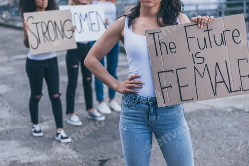 Preview: cropped view of girl holding placard with the future is female letters while standing with hand on