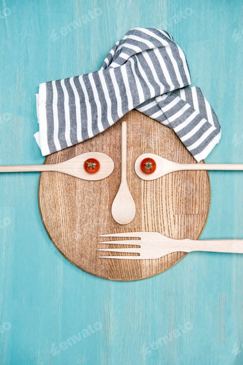 Preview: top view of wooden cooking utensils with tomatoes in form of face on kitchen board