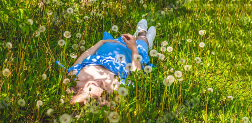 Preview: Pregnant woman with dandelions in the garden. Selective focus.