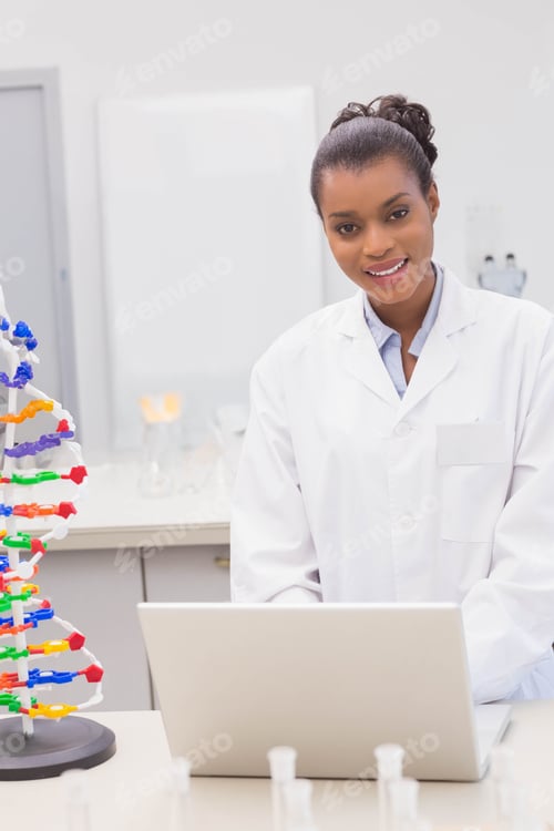Preview: African American female scientist using laptop at lab bench with DNA model and test tubes