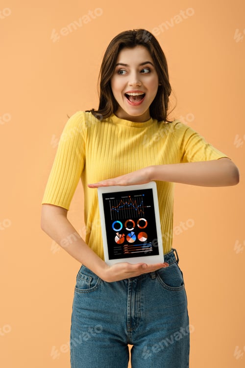 Preview: Happy brunette girl holding digital tablet with business app on screen isolated on orange