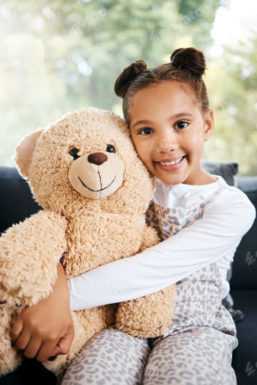 Preview: Portrait of an adorable little hispanic girl holding a teddy bear at home. Cute mixed race girl pla