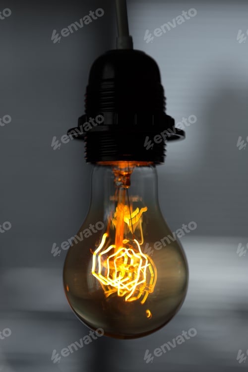 Preview: A classic Edison light bulb on dark background with space for text