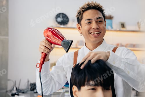 Preview: Young hairdresser using hairdryer on client