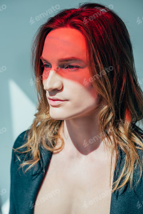 Preview: handsome man with long hair and red light on face, on grey