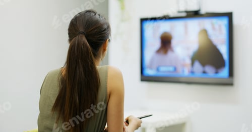 Preview: Woman watch TV at home and sit on sofa
