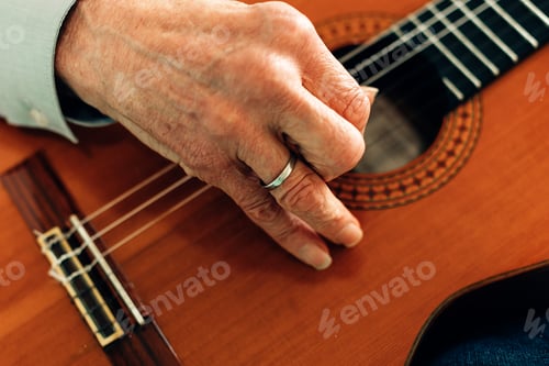 Preview: close up on the hands of an old guitarist playing acoustic guitar