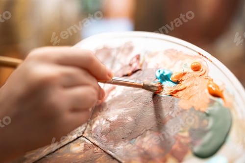 Preview: Talented artist painting an artwork with colorful paints mixed on a palette