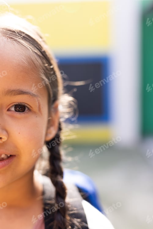 Preview: Vertical half face portrait of smiling cauasian elementary schoolgirl in schoolyard, copy space