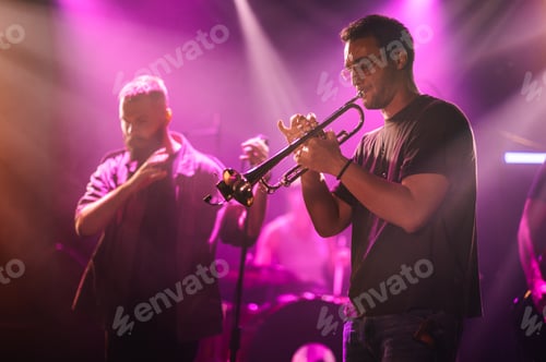 Preview: Trumpet player performing live music on stage with band in purple light
