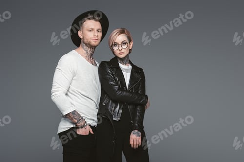 Preview: stylish tattooed couple posing together, isolated on grey