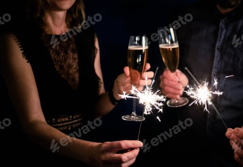 Visualização: casal segurando brilhos e taças de champanhe Feliz Ano Novo