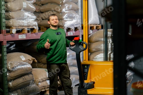 Preview: worker posing at a coffee factory a man with a yellow forklift behind him is carrying bags of coffee
