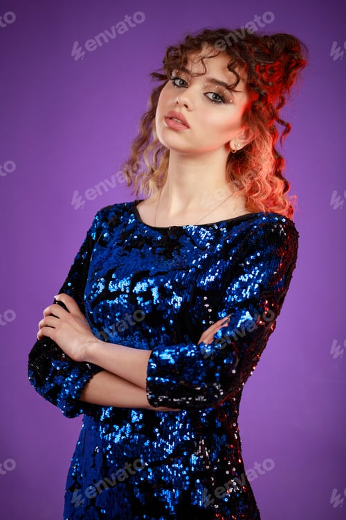 Preview: A vertical portrait of a young lady crossed her hands and looked at the camera on purple background.