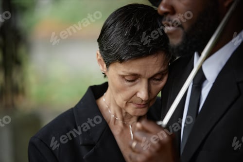 Preview: Senior Woman Grieving on Mans Shoulder in Memorial Ceremony at Cemetery