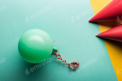 Preview: Top view of green balloon and red party hats on tiffany and yellow background
