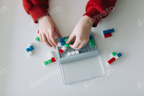 Vorschau: Nahaufnahme Hände eines Kindes, das an einem weißen Tisch spielt, sammelt ein Puzzle