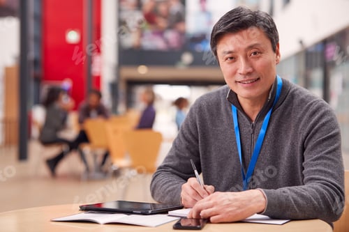 Preview: Portrait Of Mature Male Teacher Or Student With Digital Tablet Working At Table In College Hall