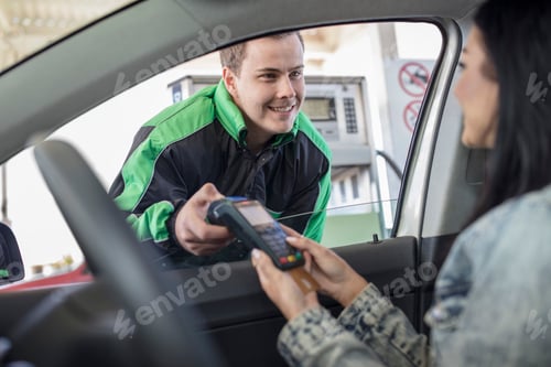 Preview: Female customer paying with credit card at the fuel station