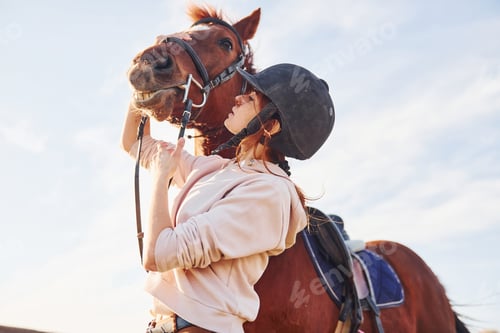 Preview: Beautiful sunshine. Young woman standing with her horse in agriculture field at daytime