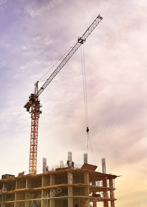 Preview: construction crane lifts a concrete slab against the background of a sunset sky and a multi-storey