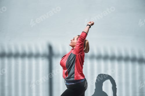 Preview: Side view of young plus size woman in sports clothing stretching