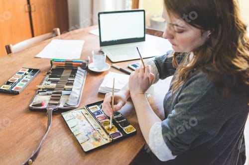 Preview: Young caucasian illustrator woman dipping brush using computer